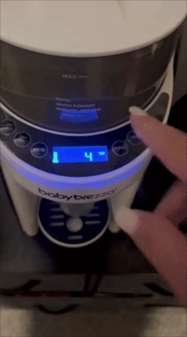 Finger pressing buttons on a Baby Brezza formula dispenser to set 4 ounces