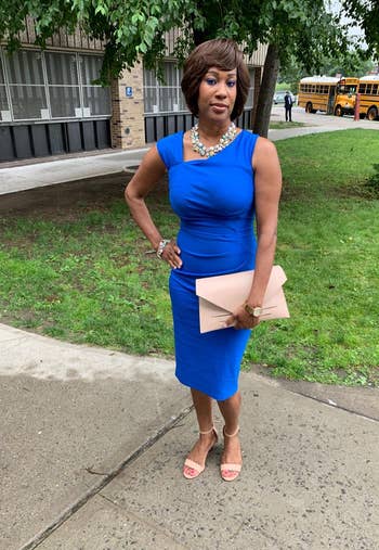 reviewer wearing a dress in royal blue with a clutch and chunky necklace