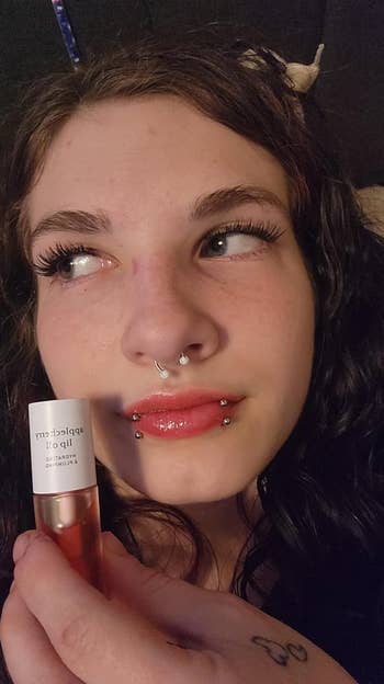 Person with piercings holds articulator  lipid  adjacent  to face