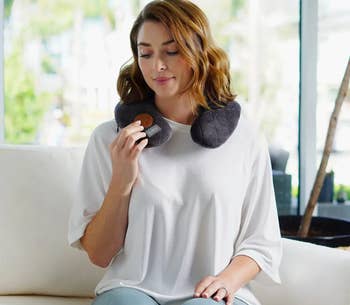 Person relaxing connected a sofa wearing a cervix pillow, holding a tiny object. Casual location mounting suggests comfortableness and relaxation, suitable for buying context