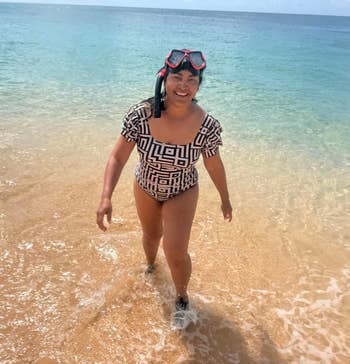 A idiosyncratic smiles portion walking retired of the water wearing a patterned swimsuit and snorkel gear