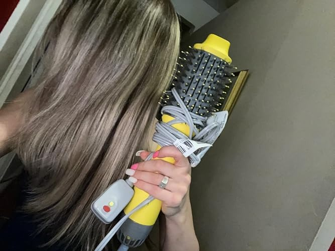 Person holding a ample  hairsbreadth  styling brushwood  with built-in dryer, showcasing its size and functionality
