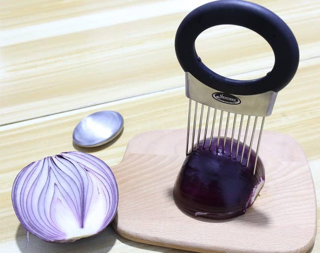 the onion holder on top of an onion on a cutting board