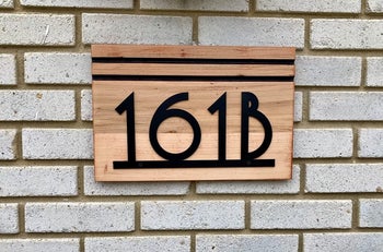 reviewer image of metal house numbers 161B on a plank of wood on a brick house