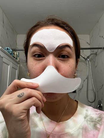 A reviewer applies a facial skin care mask on their forehead