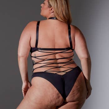 same model in a strappy black bodysuit, viewed from behind