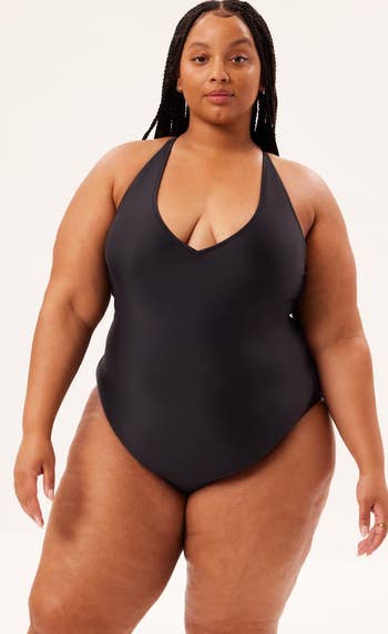 a model wearing a black one-piece swimsuit with a plunging V-neck 