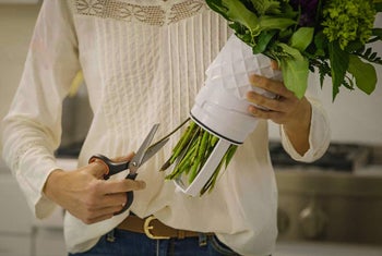 Model cutting the stems of the flowers and draining the water 