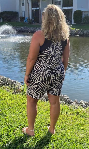 Woman in a black and white patterned romper by a pond
