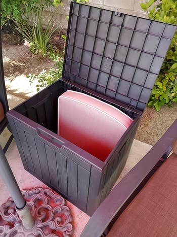 Outdoor storage box open revealing red cushion inside