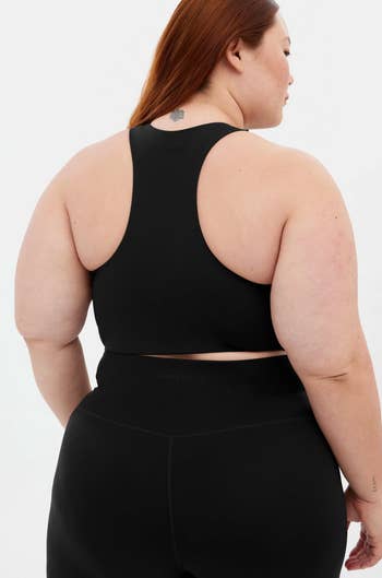Person wearing a achromatic diversion vessel apical and leggings, viewed from the back, showcasing activewear acceptable and style