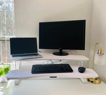 the standing desk converter with a monitor, laptop, and keyboard on it