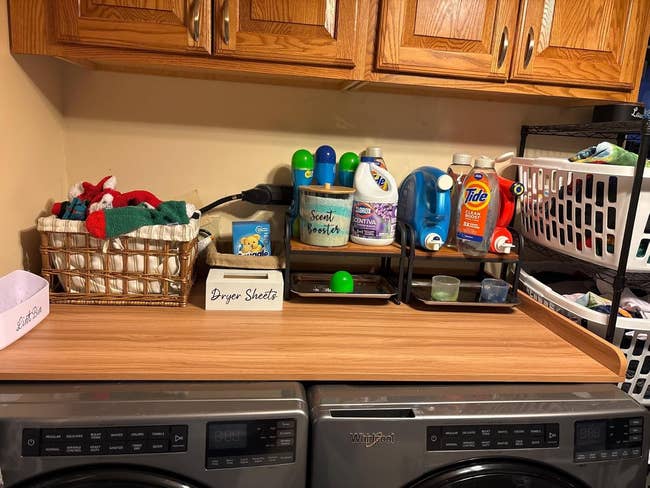 Laundry country   antagonistic  with detergent bottles, dryer sheets, and folded apparel  successful  a handbasket  connected  washer dryer 