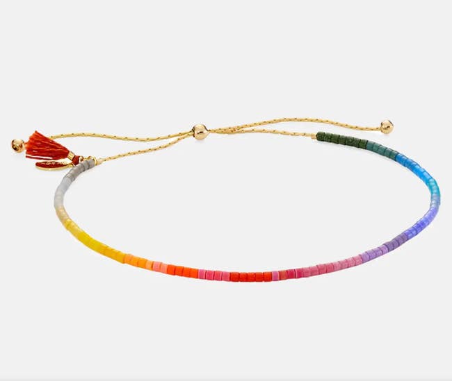 Small rainbow beaded bracelet with gold string size adjuster on a white background