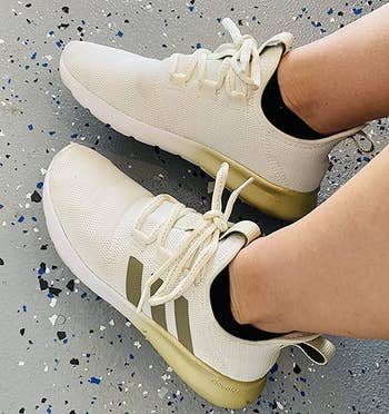 a reviewer wearing the sneakers in white with metallic gold detailing 