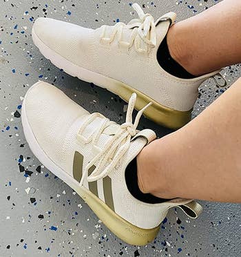 a reviewer wearing the sneakers in white with metallic gold detailing 