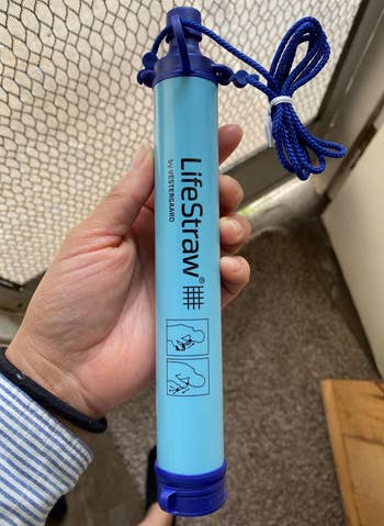 reviewer holding the blue lifestraw