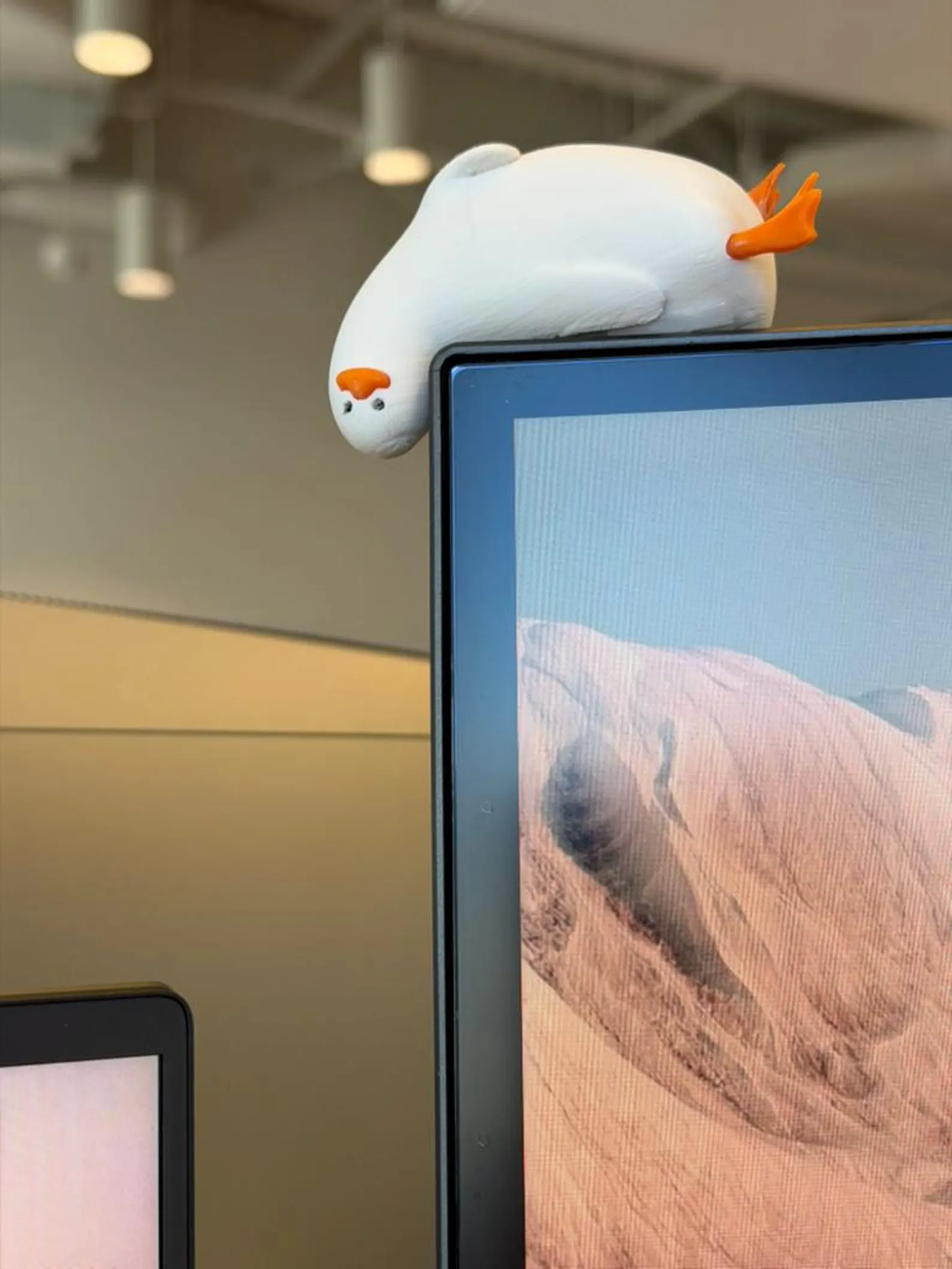 Seal-shaped desk buddy perched on a monitor, adding a playful touch to the office setup