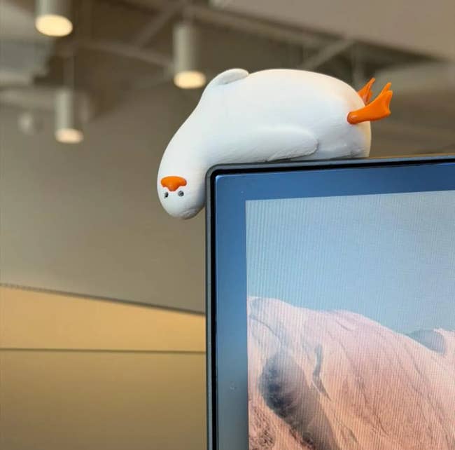 Seal-shaped desk buddy perched on a monitor, adding a playful touch to the office setup