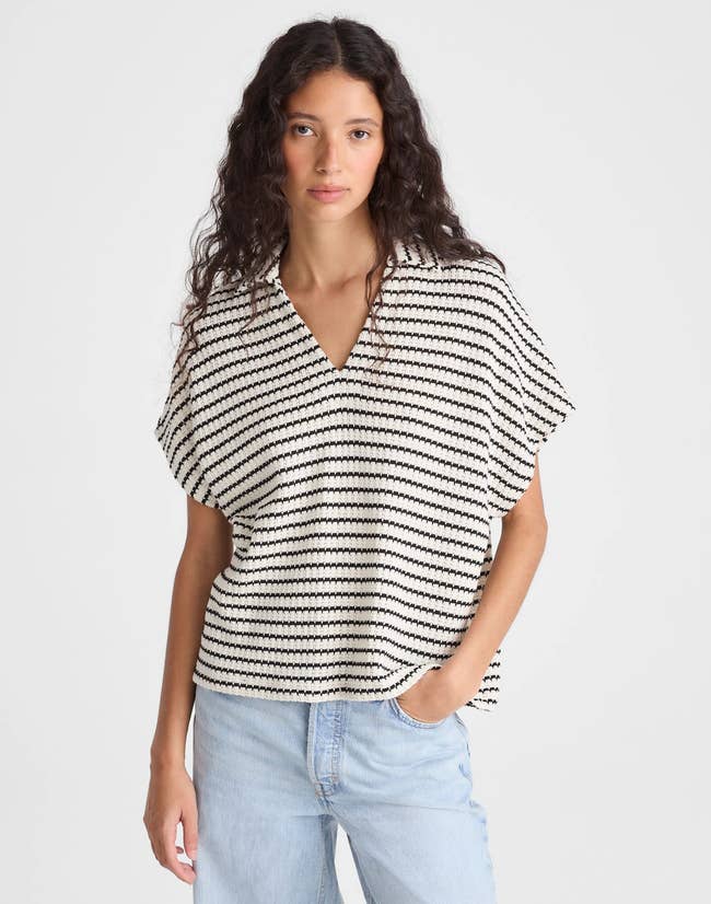 A person wears a casual, short-sleeve, black-and-white striped top paired with light denim jeans