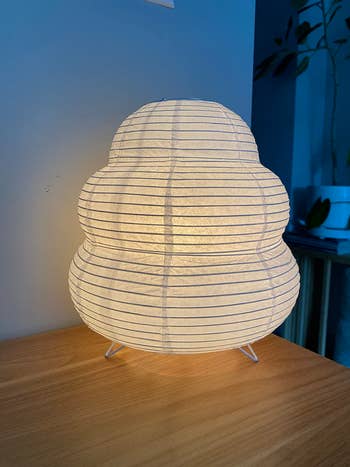 A sculptural insubstantial  lamp with horizontal lines, resting connected  a woody  table, creates a soft, ambient glow successful  a minimalist room
