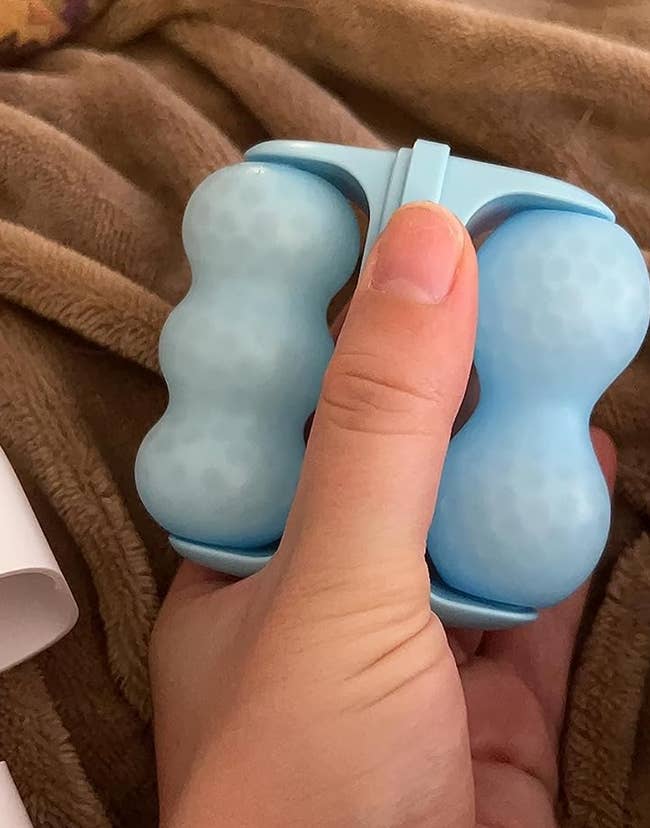 reviewer holding small blue dual sided ice roller 