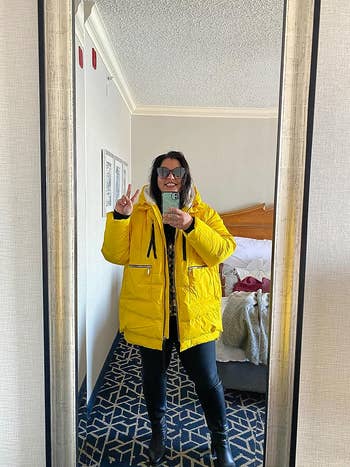 A reviewer taking a mirror selfie while wearing the coat in yellow