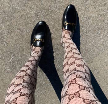 reviewer wearing patterned tights with Gucci logo on them paired with the black slip-on mules