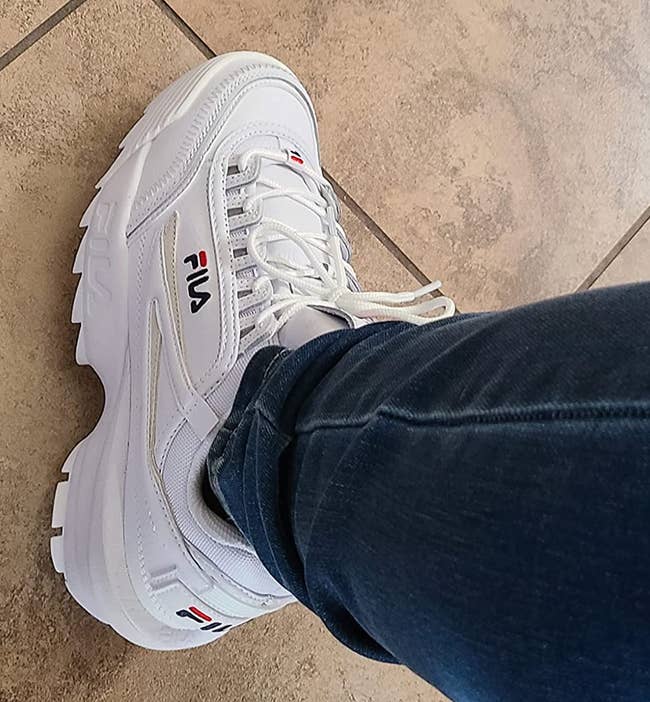 reviewer wearing the white Fila sneakers