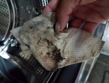 reviewer showing a used wipe covered in gunk it removed from the washer