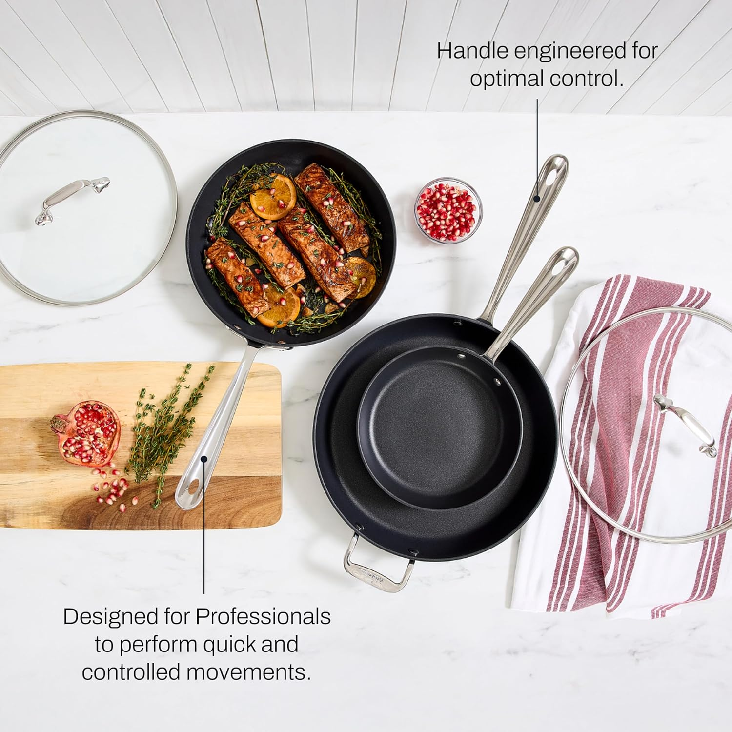 Cookware acceptable   with 2  pans and lids, serving salmon garnished with herbs and pomegranates connected  a board; designed for nonrecreational  cooking control