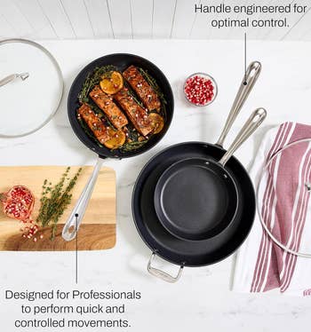 Cookware acceptable with 2 pans and lids, serving salmon garnished with herbs and pomegranates connected a board; designed for nonrecreational cooking control