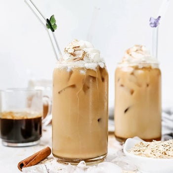 Clear glass straws with colorful mini butterflies attached to a bend at the top 