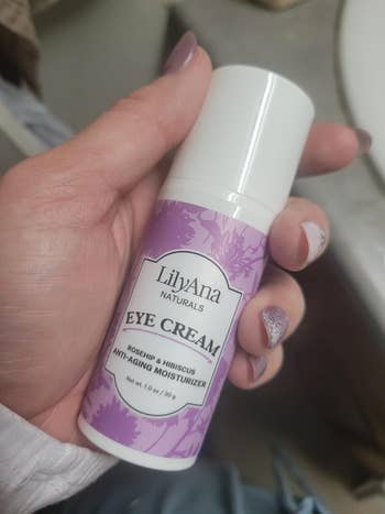 Sebuah tangan memegang sebotol Krim Mata LilyAna Naturals