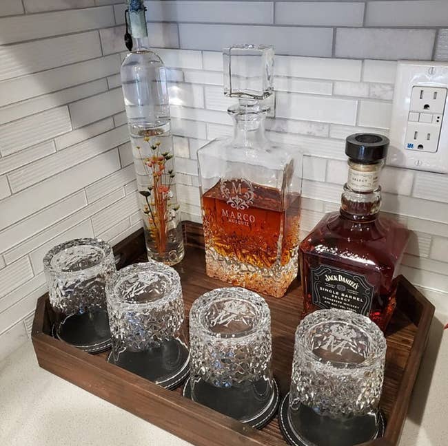 The personalized, glass decanter set on a brown wood tray. It includes the four glasses with an 