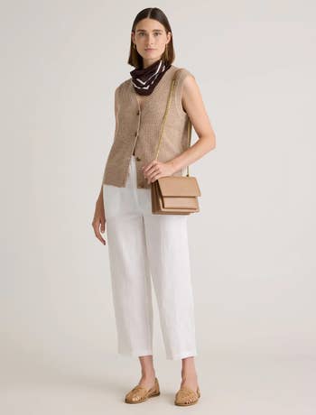 A idiosyncratic   models a sleeveless knit vest, achromatic  pants, and loafers 