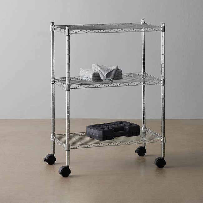 A three-shelf metal kitchen cart with wheels on the bottom 
