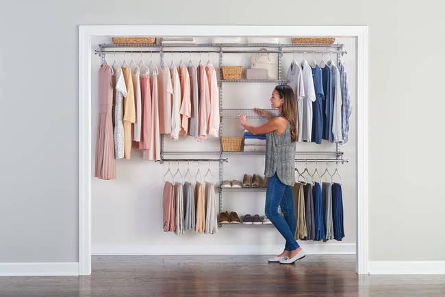 Model organizing a well-organized closet with neatly hung garments and shoes