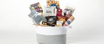 Gift basket with various gourmet snacks, including caramel popcorn, peanut crunch, tea, and chocolates, ideal for a shopping guide or holiday gift recommendation