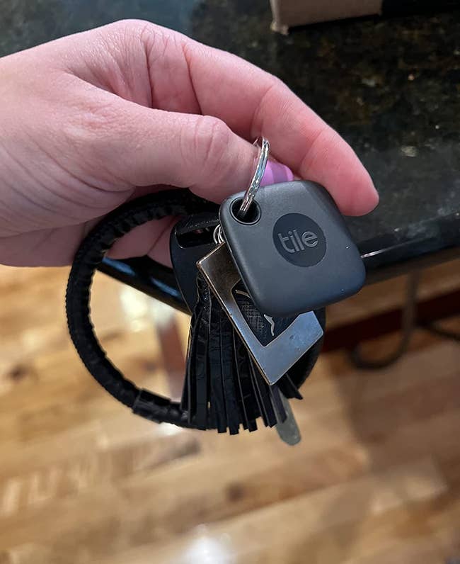 A reviewer holding their keychain with their keys and key alarm attached