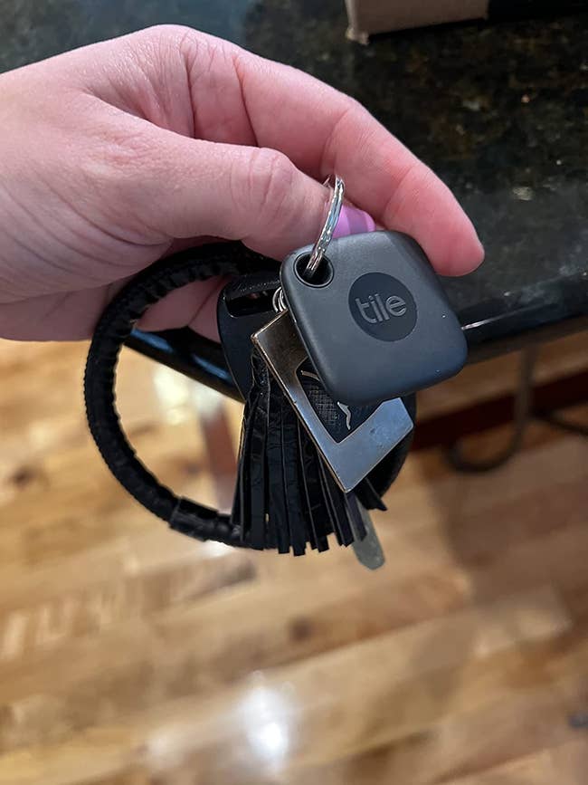 A reviewer holding their keychain with their keys and Tile Mate attached