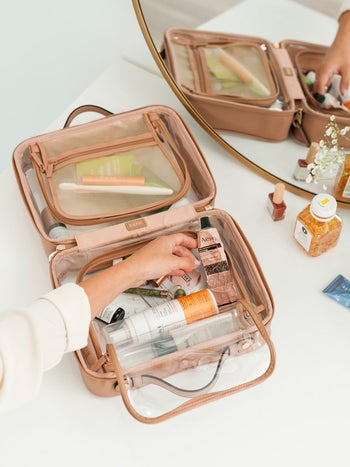 model hand filling the open clear makeup bag with tan edges