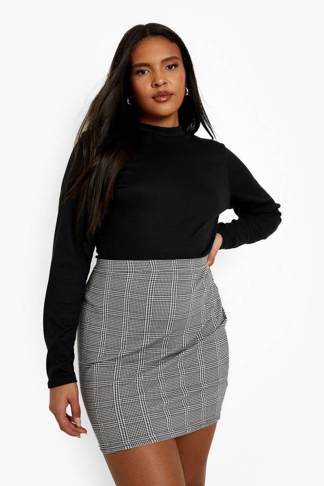 model wearing the gray skirt with a black long-sleeve sweater tucked into it