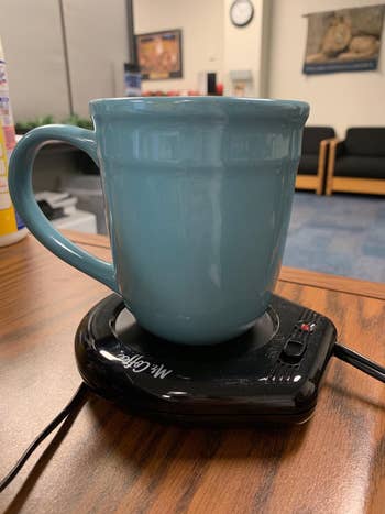 reviewer photo of their blue mug resting on the black mug warmer