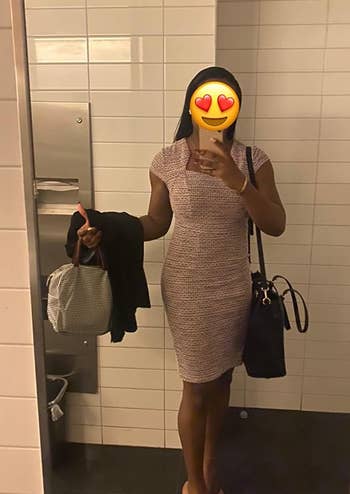Person taking a mirror selfie, holding a jacket and bag, wearing a sleeveless tweed dress, suitable for a business casual look