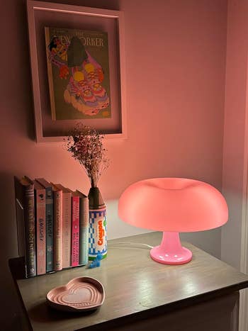 the pink retro lamp on a desk next to books