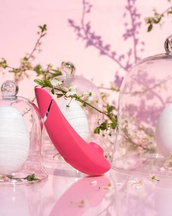Pink suction vibrator next to flowers