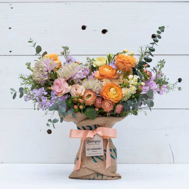 a bouquet of flowers in shades of peach, pink, and lavender