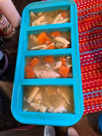 reviewer photo of a blue silicone ice tray with chicken noodle soup in it