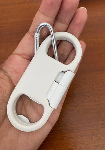 Hand holding a white multi-tool keychian with a charger 